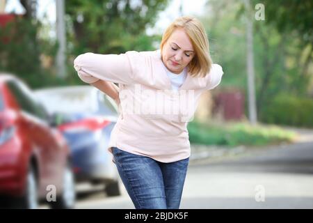 Donna anziana che soffre di mal di schiena all'aperto Foto Stock