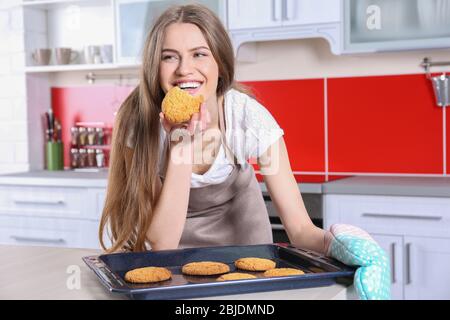 Giovane donna con biscotti su teglia in cucina Foto Stock
