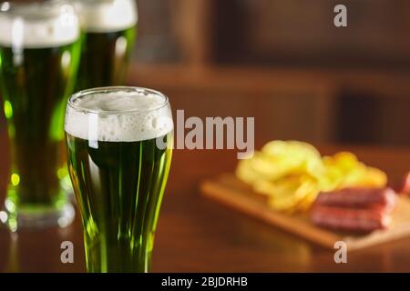 Concetto di San Patrizio Day. Bicchiere di birra verde e snack al banco bar Foto Stock