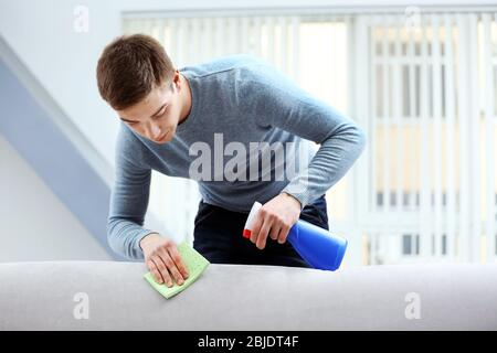 Lavoratore di sesso maschile che rimuove lo sporco dal divano con un  aspirapolvere professionale in ambienti interni Foto stock - Alamy