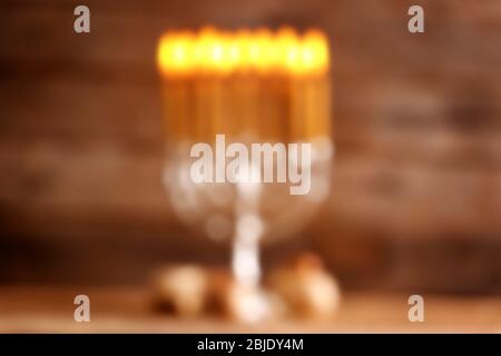 Vista sfocata del menorah con candele per Hanukkah sul tavolo contro sfondo di legno Foto Stock