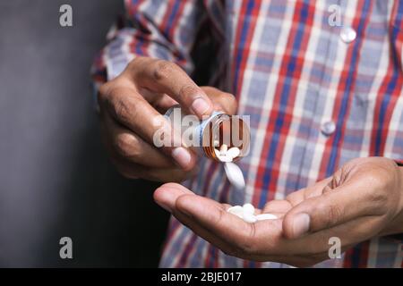 Versando le pillole dalla bottiglia bianca nel palmo Foto Stock