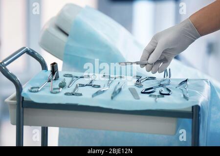 Chirurgo mano che prende lancet da tavolo speciale in clinica Foto Stock