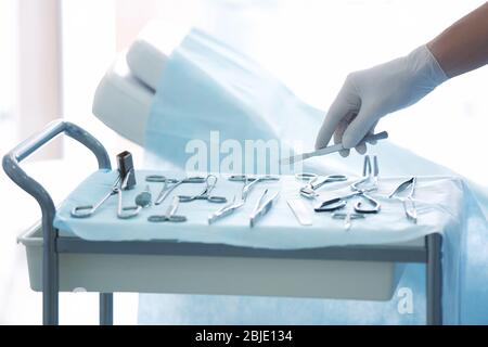 Chirurgo mano che prende lancet da tavolo speciale in clinica Foto Stock