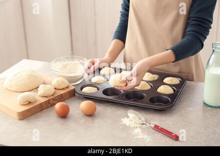 Donna che mette piccole palle di pasta in forma di cottura in cucina Foto Stock