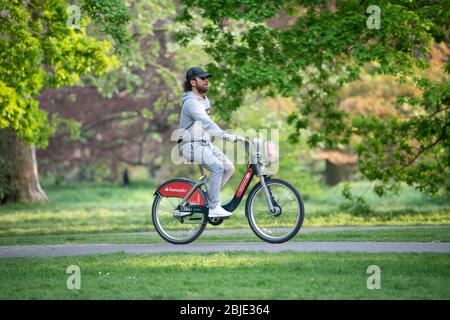 Ciclista su bici Santander noleggiata indossando guanti protettivi e a Londra Lockdown. Foto Stock