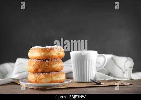 Gustose ciambelle con tazza di caffè su sfondo grigio Foto Stock