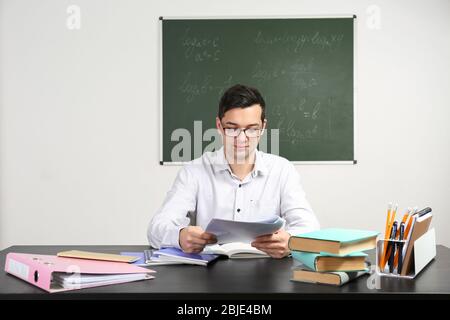 Bel giovane insegnante seduta a tavola in aula Foto Stock