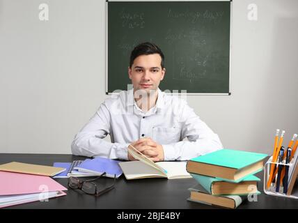 Bel giovane insegnante seduta a tavola in aula Foto Stock