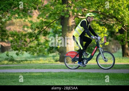 Ciclista su bici Santander noleggiata indossando guanti protettivi e a Londra Lockdown. Foto Stock