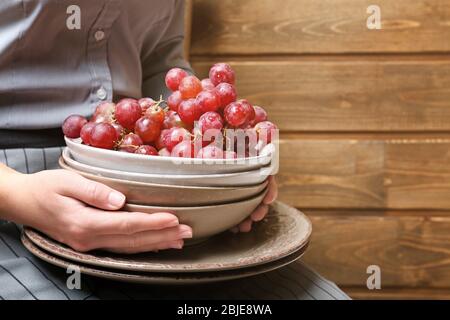 Mani femminili che tengono ciotole con uva, primo piano Foto Stock