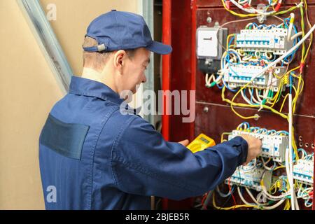 Elettricista misurando la tensione nella scheda di distribuzione Foto Stock