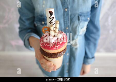 Ragazza che tiene milkshake con ciambelle e altri dolci in vetro Foto Stock