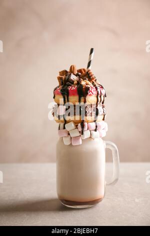 Milkshake, ciambelle e altri dolci in vaso su tavola Foto Stock