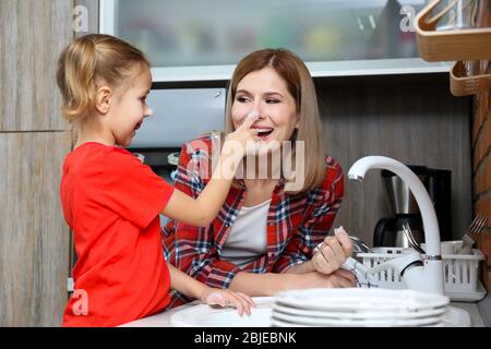 La bambina e la madre lavano i piatti a casa Foto Stock