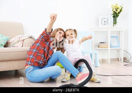 Bambina e sua madre giocando mentre fa pulizia a casa Foto Stock