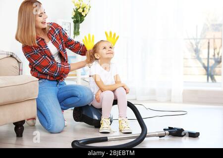 Bambina e sua madre giocando mentre fa pulizia a casa Foto Stock