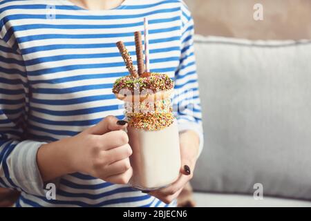 Ragazza che tiene milkshake con ciambella e altri dolci in vaso Foto Stock