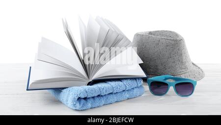 Concetto di vacanza. Libro, asciugamano e cappello su tavolo di legno bianco Foto Stock