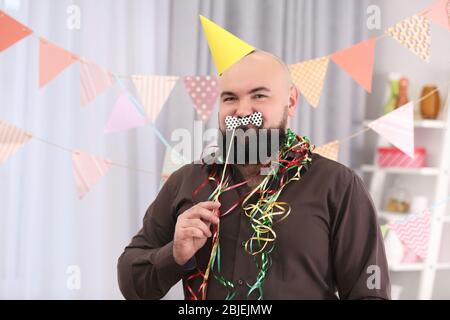 Divertente grasso uomo che celebra il compleanno a casa Foto Stock