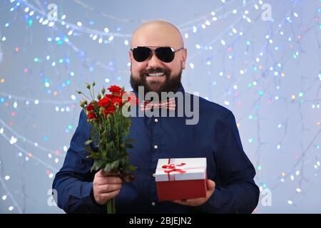 Divertente uomo grasso con giftbox e fiori alla festa di compleanno Foto Stock