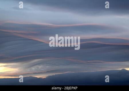 Covate nuvole cattura un accenno di tramonto lungo il loro bordo. Foto Stock