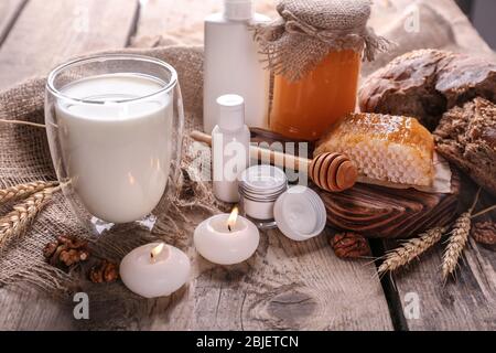 Latte, miele e cosmetici su sfondo di legno Foto Stock