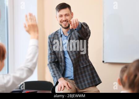 Alunni che ascoltano l'insegnante e che alzano le mani per rispondere in classe Foto Stock