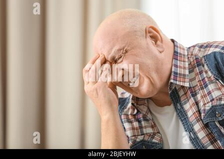 Senior l uomo che soffre di mal di testa a casa Foto Stock