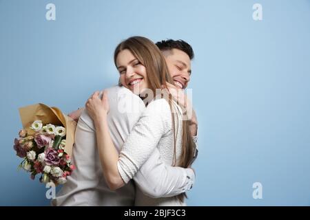 Giovane coppia felice con bouquet di fiori su sfondo chiaro Foto Stock