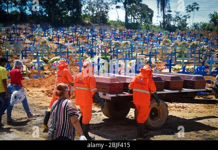 Manaus, Brasile. 29 aprile 2020. I lavoratori del cimitero, seguiti dai parenti dei morti che indossano maschere facciali contro la diffusione di Covid-19, guidano le bare verso una tomba di massa. In considerazione del numero crescente di infezioni da corona, il servizio sanitario di Manaus è al suo limite. Un contenitore refrigerato per conservare i cadaveri è stato allestito di fronte ad un ospedale, sono state scavate tombe di massa. Il numero di decessi correlati a Covid-19 nel paese è salito a 5017, superando la Cina, che ha ufficialmente registrato 4643 morti. Il presidente di estrema destra Bolsonaro gioca il virus. Credit: Chico Batata/dpa/Alamy Live News Foto Stock