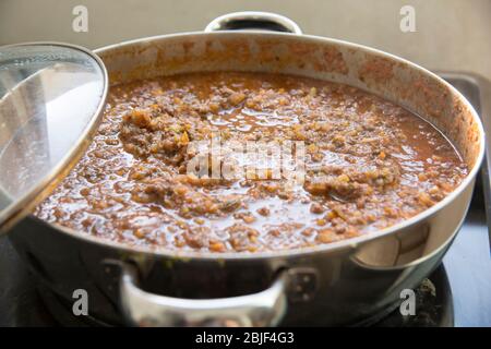 Vista dall'alto di una salsa bolognese fatta in casa (Ragù alla bolognese) con basilico fresco (Basilio d'Ocimum) in una pentola. Foto Stock