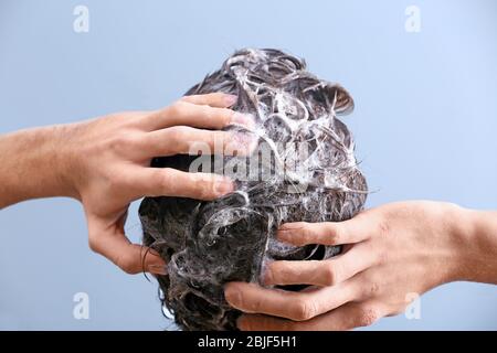 Giovane uomo che lava i capelli su sfondo colore Foto Stock