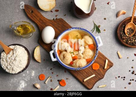 Porzione di delizioso pollo e gnocchi in una zuppa decorativa pentola sul tavolo da cucina Foto Stock