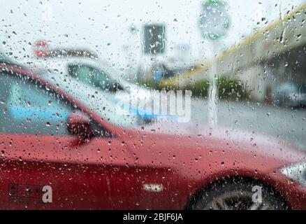 Le auto fuori fuoco parcheggiate nel parcheggio dell'ASDA, Brighton Marina, fotografate attraverso la finestra dell'auto con le gocce di pioggia. East Sussex, Regno Unito Foto Stock