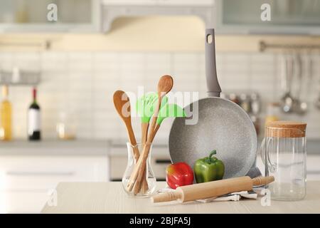 Utensili da cucina, pentole e peperoni su tavolo di legno Foto Stock