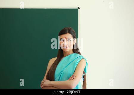 Ritratto di insegnante femminile indiano vicino a lavagna in classe Foto Stock