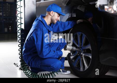 Giovane meccanico cambio ruota in servizio auto Foto Stock