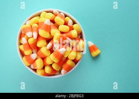 Ciotola con gustose caramelle di Halloween su sfondo colorato Foto Stock