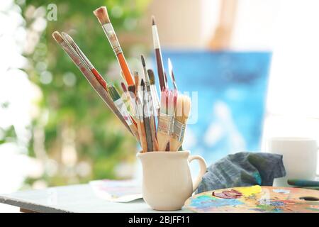 Tazza con accessori per artisti sul tavolo Foto Stock