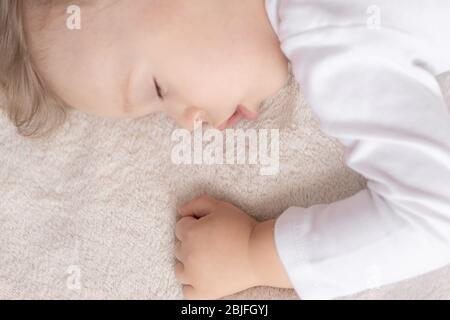 Infanzia, sonno, riposo, famiglia, stile di vita concetto - ritratto ravvicinato di un bambino carino di 2 anni in un corpo bianco che dorme su un letto beige a. Foto Stock