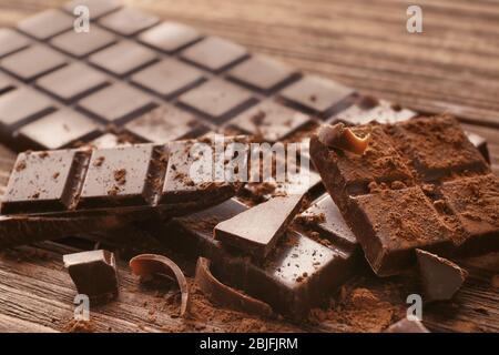 Rotture di pezzetti di cioccolato e cacao in polvere su sfondo di legno Foto Stock