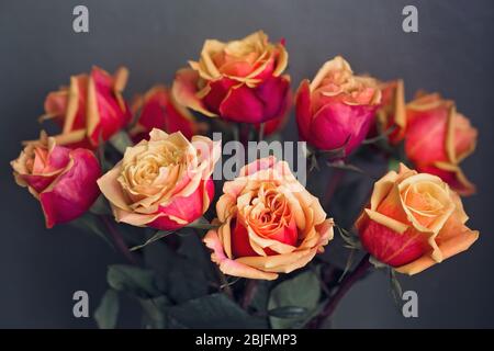 Bouquet di rose rosse e arancioni davanti a sfondo scuro Foto Stock