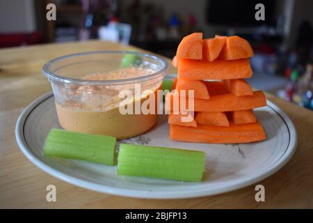 Carote piramide bastoni di sedano pronti per immergersi in hummus. Miscela spessa di purè di ceci, olio tahini, succo di limone e aglio utilizzati come piatto di pane pita laterale Foto Stock