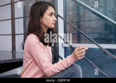 Adolescente seduto sulle scale e fumare Foto Stock