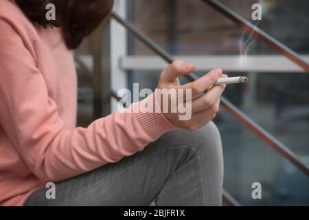 Ragazza adolescente che tiene sigaretta, closeup Foto Stock