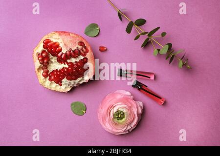 Bella composizione con campioni di profumo, melograno e fiore su sfondo colorato Foto Stock