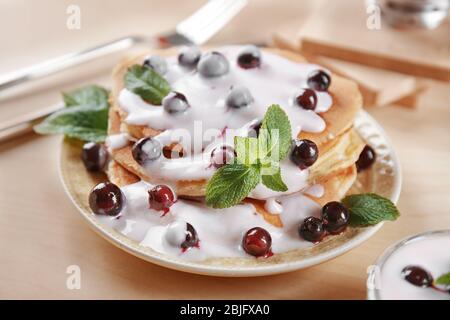 Deliziosi pancake con frutti di bosco e yogurt a piatto Foto Stock