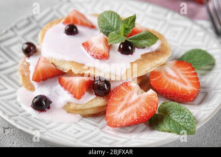 Deliziosi pancake con frutti di bosco e yogurt a piatto Foto Stock