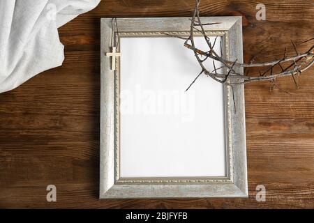 Cornice fotografica, corona di spine e croce su sfondo legno Foto Stock